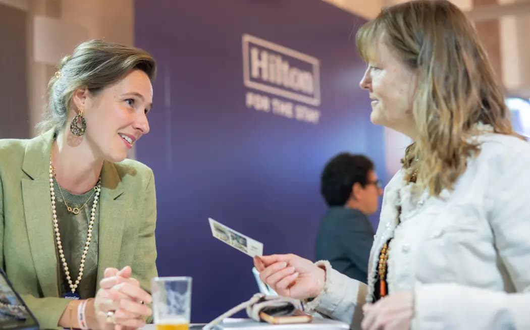 Two delegates in conversation at an M&I meeting table